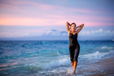 Gün batımında okyanusun kenarında güzel bir kadın