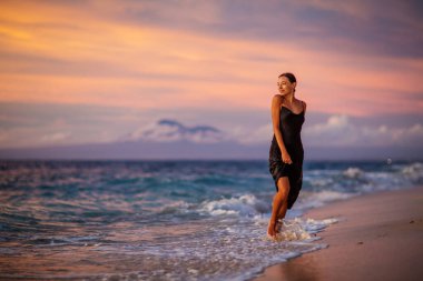 Gün batımında okyanusun kenarında güzel bir kadın