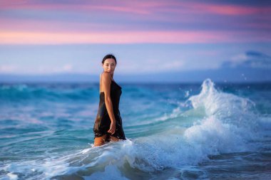 Gün batımında okyanusun kenarında güzel bir kadın