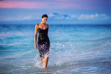 Gün batımında okyanusun kenarında güzel bir kadın