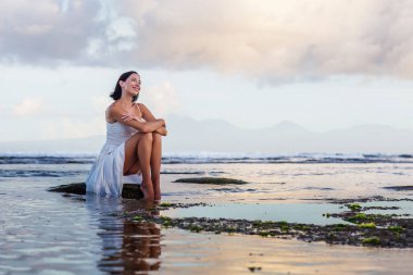 Gün batımında okyanusun kenarında güzel bir kadın