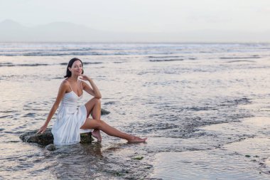 Gün batımında okyanusun kenarında güzel bir kadın