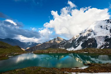 Bulutlu bir günde dağların arasında yeşil göl