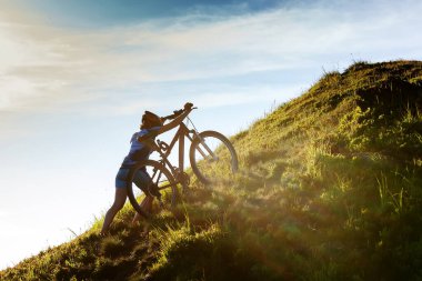 Güzel yeşil ormanda bisiklet süren bir kadın. Macera, bisiklet.