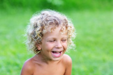 Parktaki kıvırcık beyaz bir çocuğun portresi.