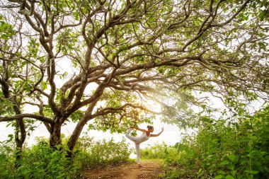 Gün batımında yoga yapan kadın.