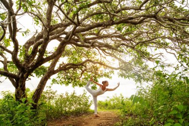 Gün batımında yoga yapan kadın.