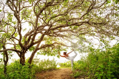 Gün batımında yoga yapan kadın.