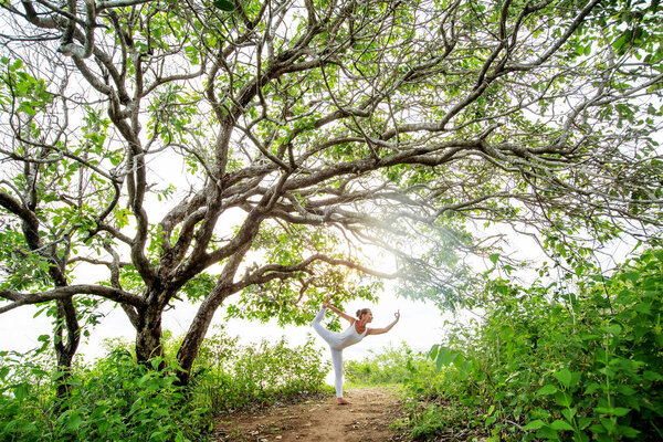 Woman practicing yoga at sunset