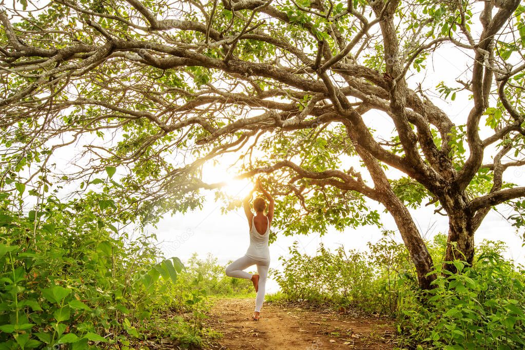 Woman practicing yoga at sunset