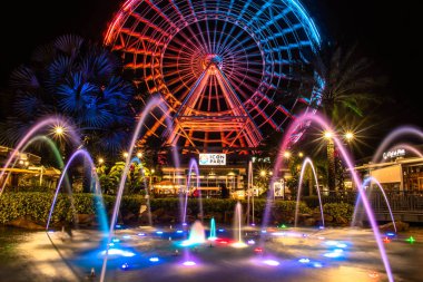 Orlando, Florida. 13 Aralık 2019. Uluslararası sürüş alanında renkli fıskiyeyle aydınlatılmış büyük tekerlek (1).