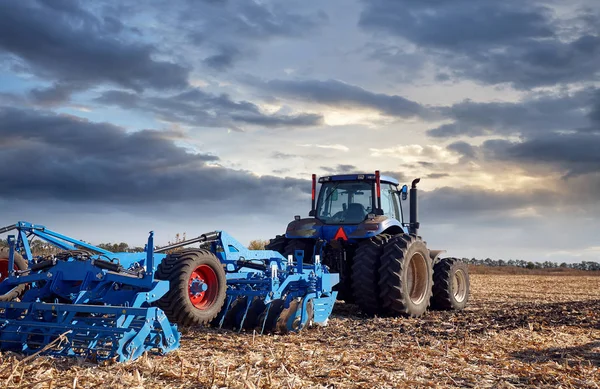 Tractor working in the field at sunset — Stock Photo, Image
