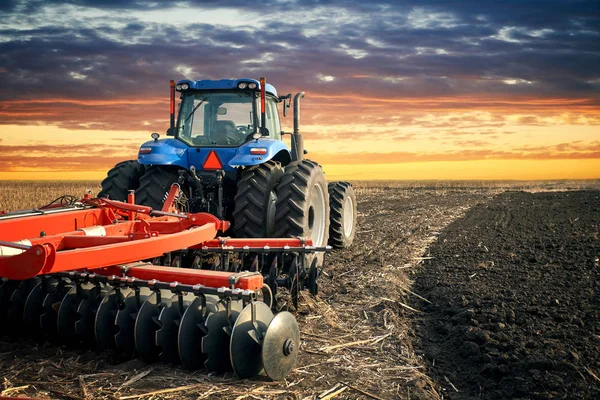 Ladang bajak traktor pada latar belakang matahari terbenam — Stok Foto