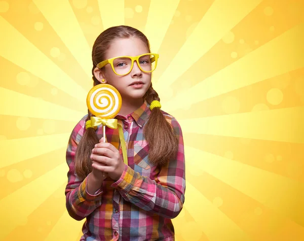 Roztomilé teen dívka s lízátkem na žlutém pozadí — Stock fotografie