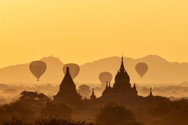 Myanmar 'da Bagan' ın üzerinde birçok sıcak hava balonuyla manzara ve çarpıcı gün doğumu. Bagan, binlerce tarihi Budist tapınağına sahip UNESCO tarafından onaylanmış antik bir şehir ve Dünya Mirası Alanıdır.