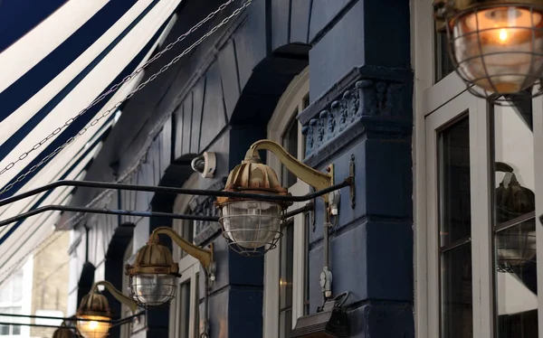 Old rusty lamps at a facade with a striped awning — Stock Photo, Image