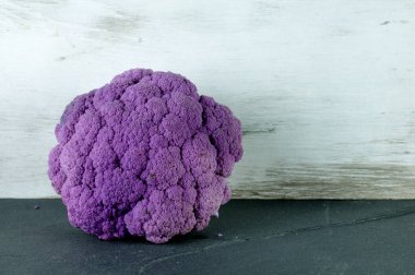 Mor karnabahar gri bir levhada yatıyor.