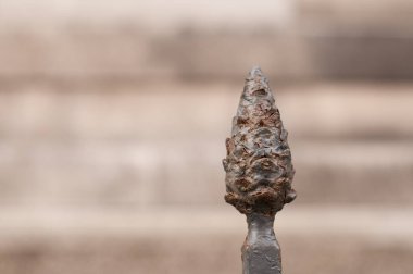 Tarihi binanın önünde, koni şeklinde dövülmüş demir bir direğin yakın çekimi.