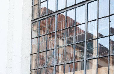 Eski boş bir fabrikada metal çerçeveli kafes penceresi