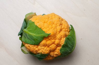 Ahşap arka planda uzanan turuncu renkli karnabahar.