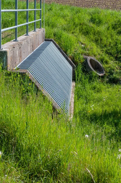 Metal şebeke ve beton boru hattıyla yüksek su hasarını önlemek için küçük bir sel kanalı.