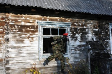 Aktif paintball oyunu. Oyun sahasının deklarasyonu, ahşap bir ev oyuncuya barınak görevi görür..