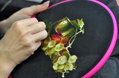 Bir kadın eli bir çemberin içine nakış işliyor, bir kadın ise karanlık maddeye bir desen işliyor. Yakın plan. Dikiş konsepti, hobi