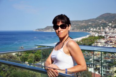 Deniz kıyısındaki tatil köyünün arka planında güzel bir kadın. Deniz Koyu.