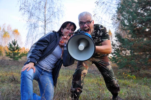 Mężczyzna i kobieta krzyczą w lesie przez megafon.. — Zdjęcie stockowe