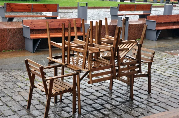 Natte tafels en stoelen in de stad straat buiten het restaurant na de regen, close-up. Einde van het buitenseizoen. — Stockfoto