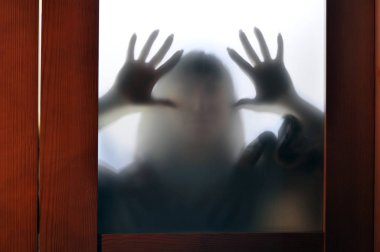 Horror woman behind the matte glass. Blurry hand and body figure abstraction.