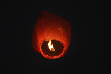 A red Chinese lantern flies in the night sky. Happy birthday summer and wedding concept.