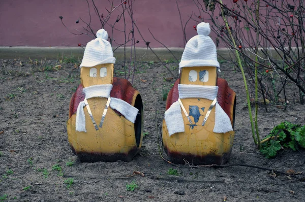 The second life of old tires. Snails made from old tires with hats and scarves on.