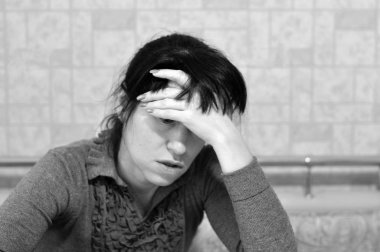 Genç bir kadın alnına eliyle dokunarak şiddetli bir baş ağrısı hisseder. Ani panik atak ya da evde endişe yaşıyor.