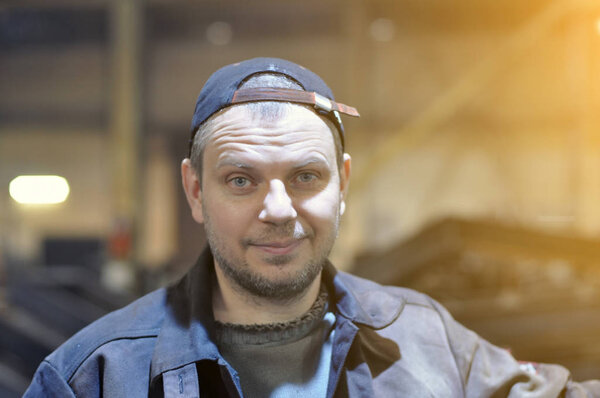 Рабочий на заводе на фоне заводской среды. Портрет
