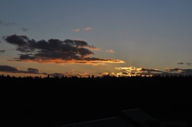 Ormanın üzerinde doğal gün batımı. Parlak dramatik gökyüzü ve karanlık dünya. Güneş ufukta, ufukta. Sıcak renkler.