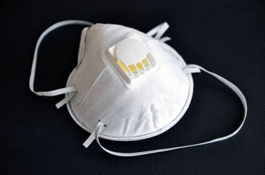 Solunum koruyucu maskesi, grip virüslerine ve koronavirüse karşı etkili, siyah arka planda. Vanalı koruyucu solunum cihazı..