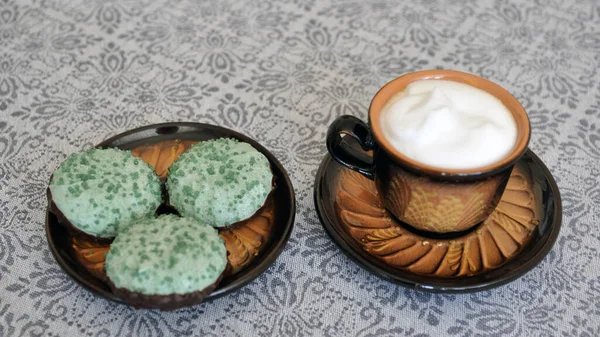 Clay cup of coffee with green marshmallows on the kitchen table. Food