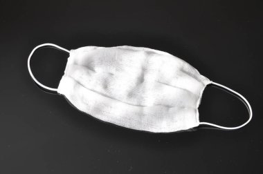 Kulağında elastik bantlarla sargı bezi, evde yapılmış, siyah bir arka planda. Solunum koruması.
