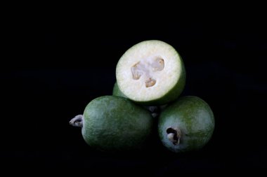 Yakın plan feijoa grubu siyah arkaplanda izole edildi. Bilimsel adı Acca sellowiana, sağlıklı ve dengeli diyet konsepti