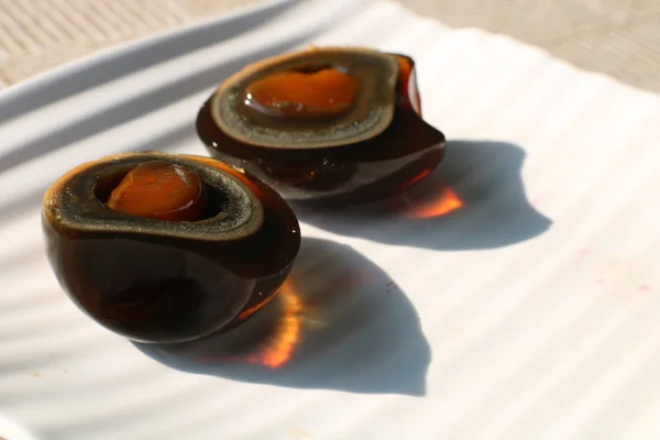 Two halves of black fermented century egg lying on white plate with bright beautiful shadows. Traditional chineese food Royalty Free Stock Photos