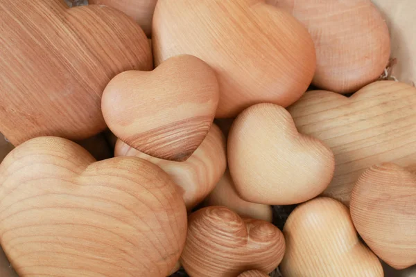 Background of big and small heart-shaped things made of wood. Horizontal