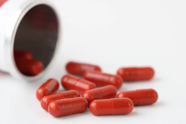 red capsules pill spilled out from white metal bottle container. Global healthcare concept. Antibiotics drug resistance. Antimicrobial capsule pills. Pharmaceutical industry. Pharmacy.