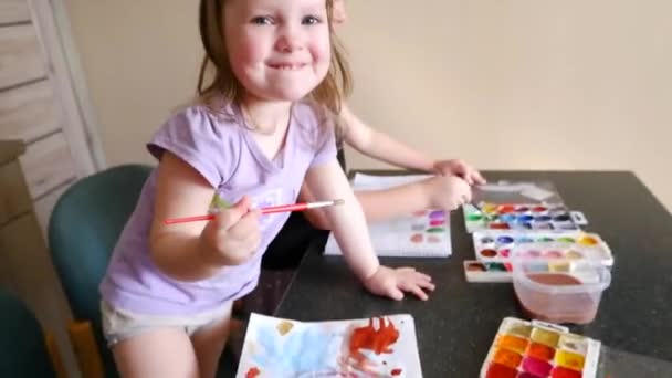 Dos hermanas niñas pintan con pinturas infantiles en una mesa de la cocina — Vídeo de stock