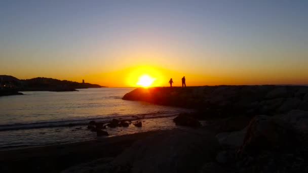 Människor som vandrar på stranden av den havet vid soluppgång — Stockvideo