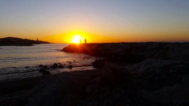 A parton sétáló emberek a a tenger, napkeltekor — Stock videók