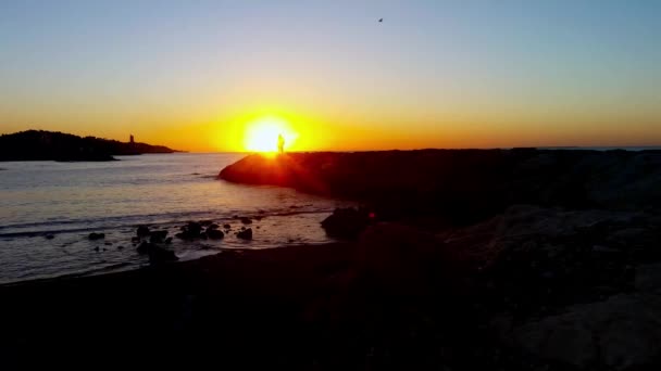 岸を歩く人、日の出の海 — ストック動画
