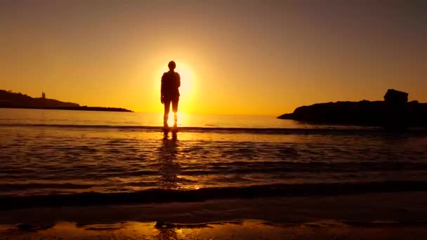 Mujer en la orilla del mar observando la puesta de sol - 4K — Vídeo de stock