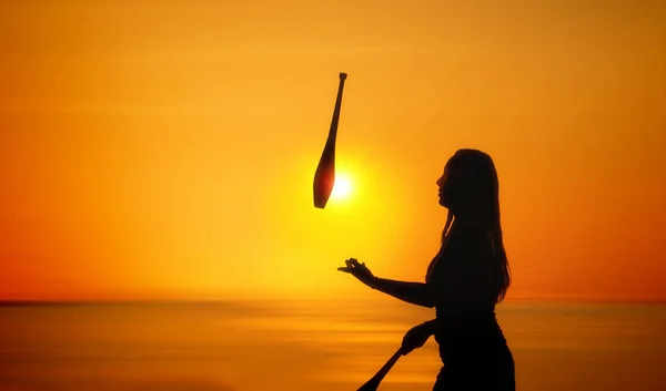 Sylwetka żonglerka kobiety na plaży o zachodzie słońca — Zdjęcie stockowe