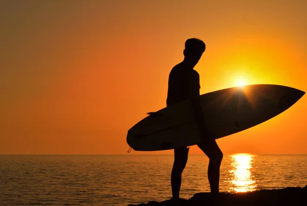 En surfare titta på vågorna vid solnedgången — Stockfoto